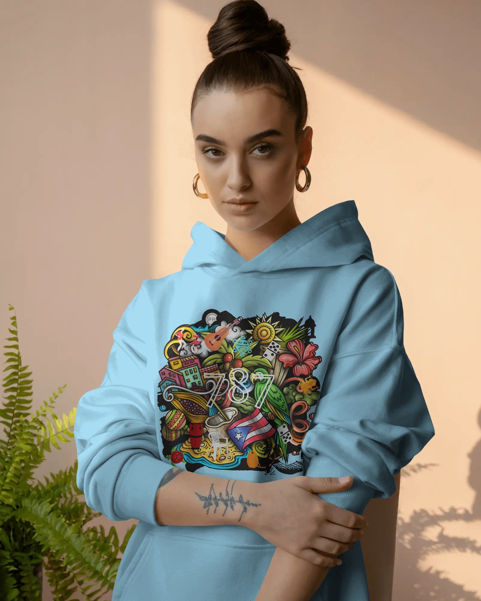 person wearing blue puerto rico hoodie displayed on a neutral background featuring a colorful puerto rico graphic with coquí frog, puerto rican flag, taíno sun, tropical flowers, palm leaves, and island-inspired cultural elements, bold boricua statement design by iron and velvet 62