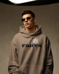 person in latte color unisex hoodie displayed on a neutral background with bold black raíces text across the chest, a white taíno sun and 787 detail, puerto rican cultural design by iron and velvet 62